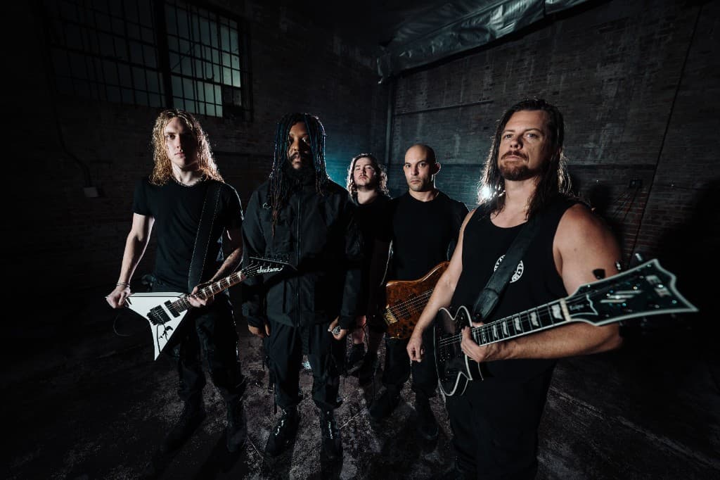 Fall of Damascus posed with guitars and bass in a dark brick warehouse