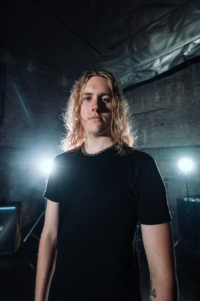 Ben of Fall of Damascus standing in front of backlit amps
